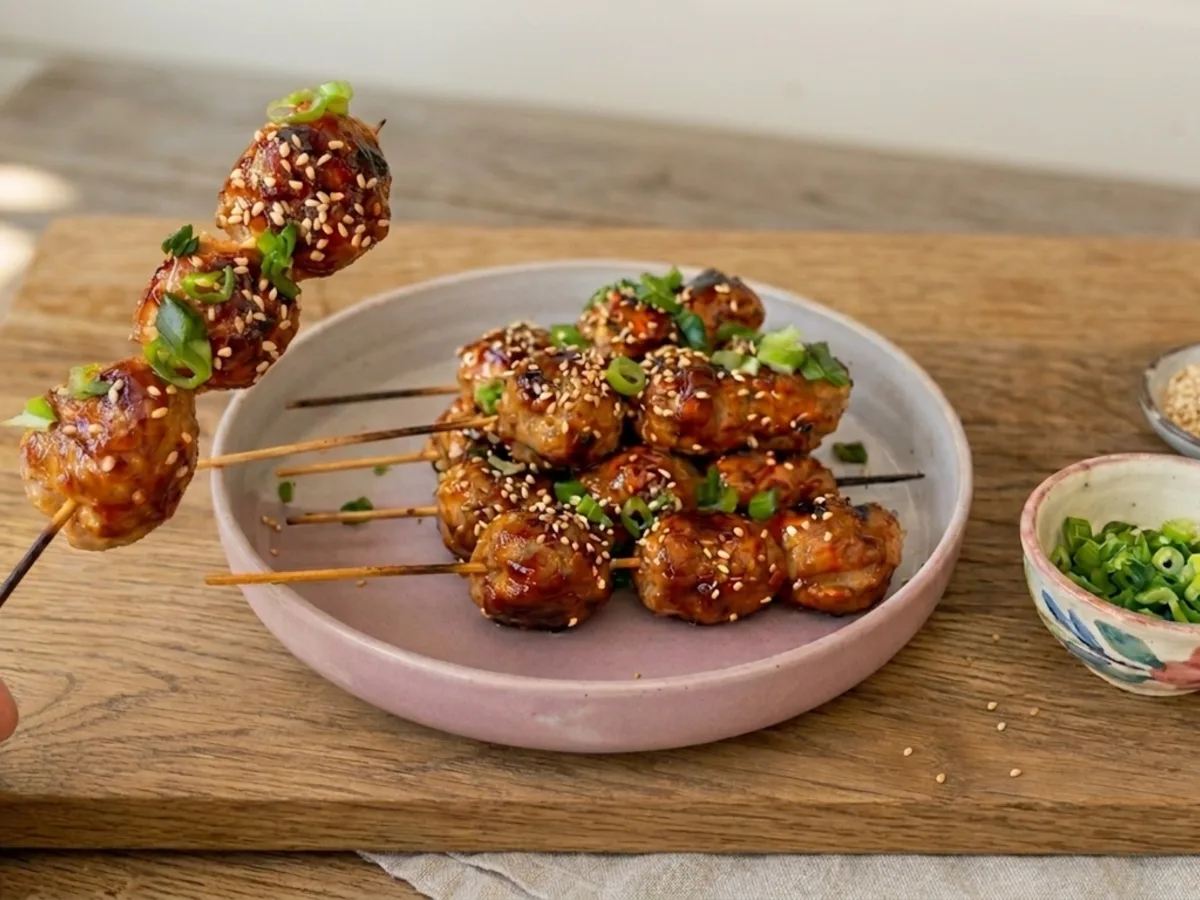 Sticky Asian chicken meatball skewers with teriyaki sauce, sesame and spring onion