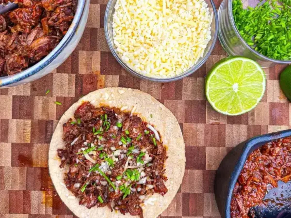 Crispy quesabirria taco with pulled beef, cheese, lime and consommé