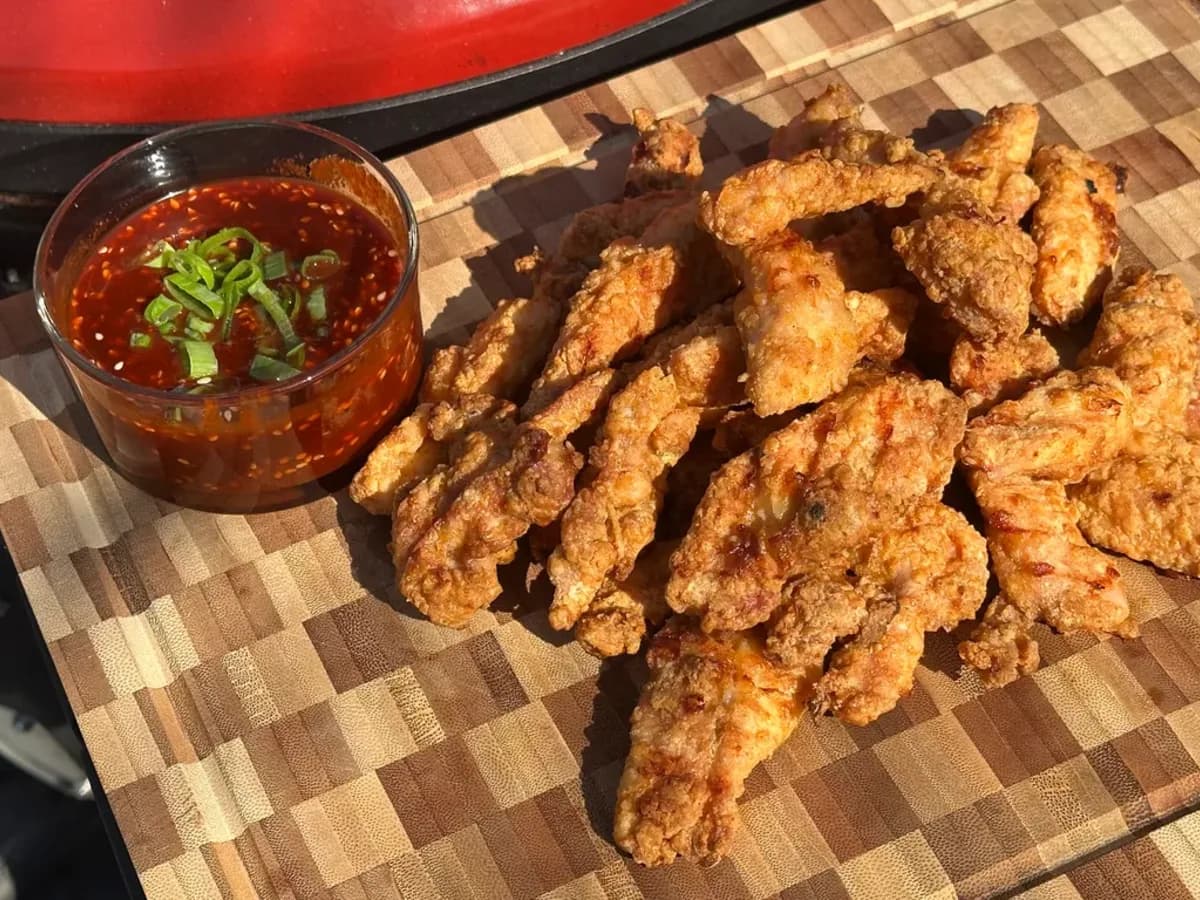 KFC-style crispy chicken filet bites with gochujang dip on a wooden board